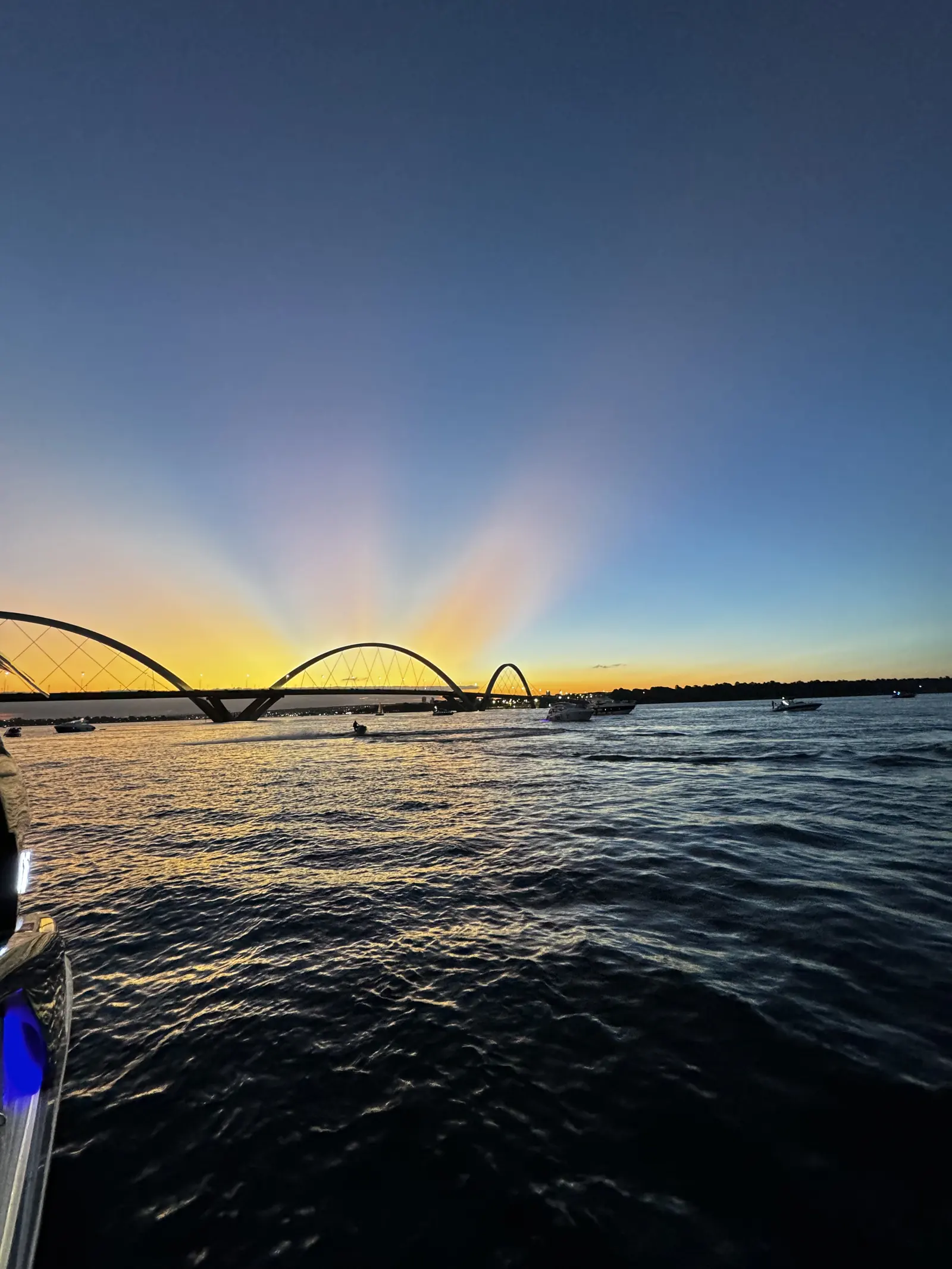 Pôr do sol no Lago Paranoá com a Ponte JK, lancha e Jet Ski navegando